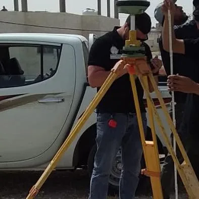 Surveyors setting up a total station beside a vehicle